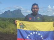 Venezuelan Indigenous man Virgilio Trujillo Arana holding the flag in front of mountains