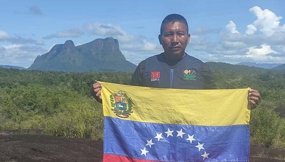 Venezuelan Indigenous man Virgilio Trujillo Arana holding the flag in front of mountains