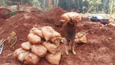 Person carrying a heavy bag of minerals in DRC