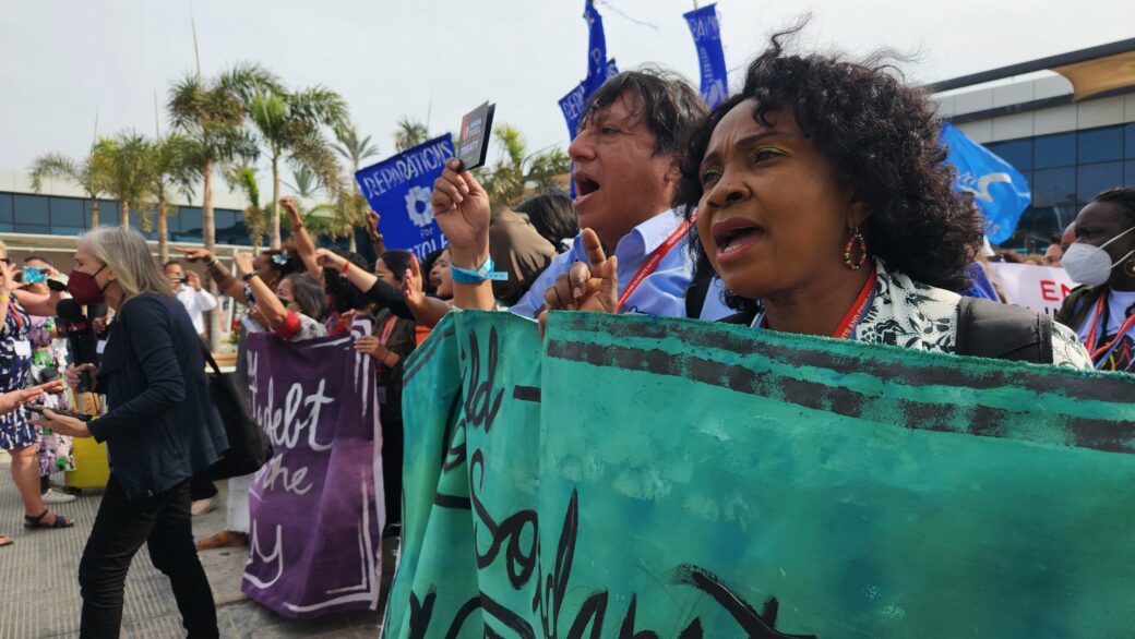 Women and men marching and holding a green banner at COP27 in Egypt, photo by Adrien Salazar