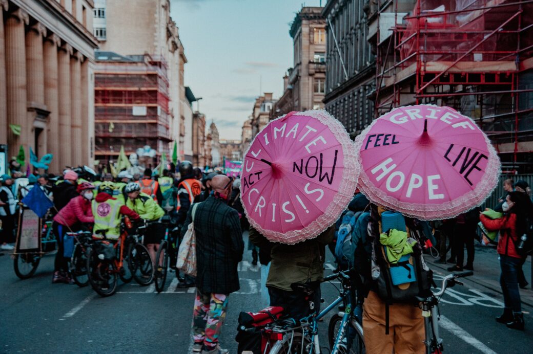 Climate action in the street at COP26 in Glasgow with pink umbrellas that say "climate crisis, act now!"