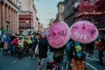 Climate action in the street at COP26 in Glasgow with pink umbrellas that say "climate crisis, act now!"