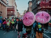 Climate action in the street at COP26 in Glasgow with pink umbrellas that say "climate crisis, act now!"