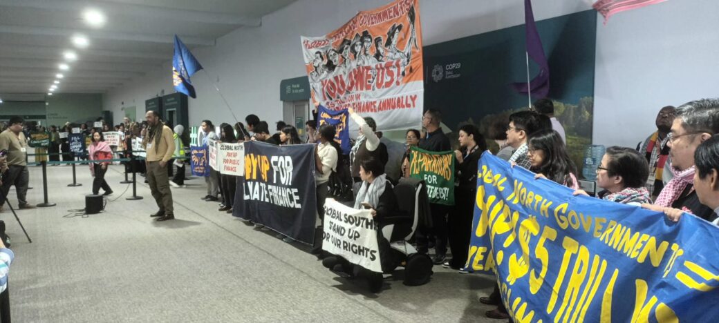 Climate justice activists at COP29 holding banners